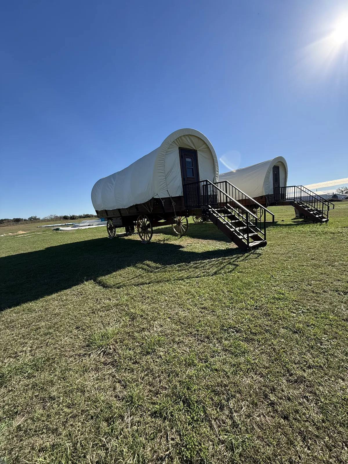 Two Conestoga wagons with stair decks under a blue sky